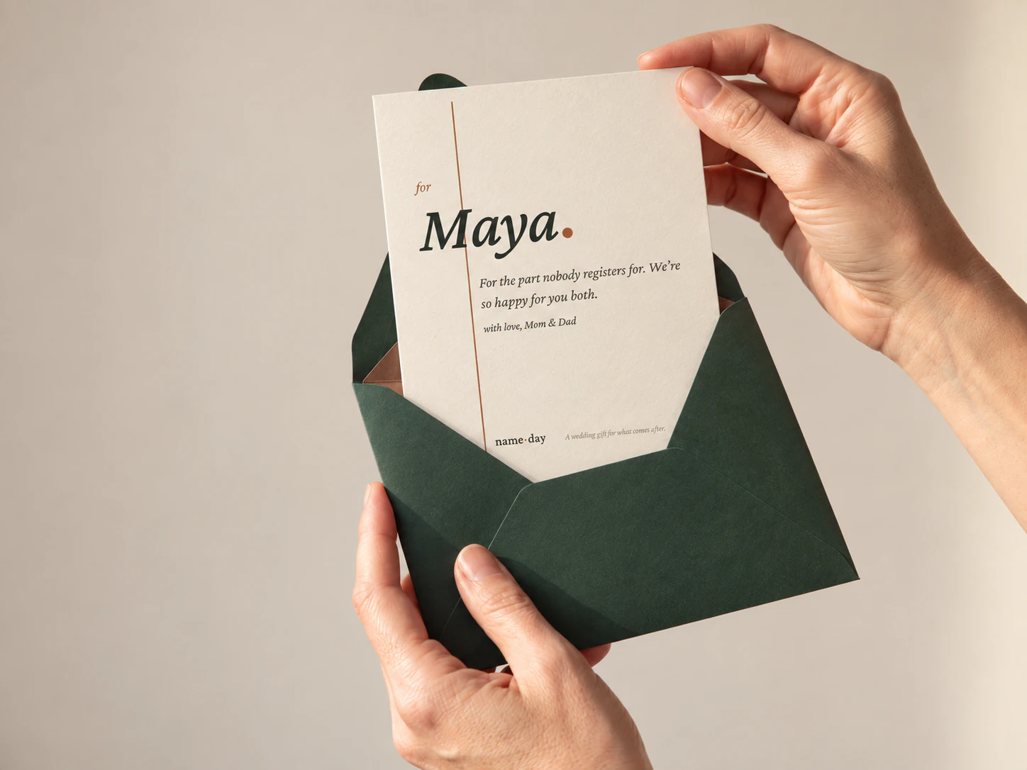 Illustrative Name Day gift: hands lifting a card personalized for Maya from a forest-green envelope
